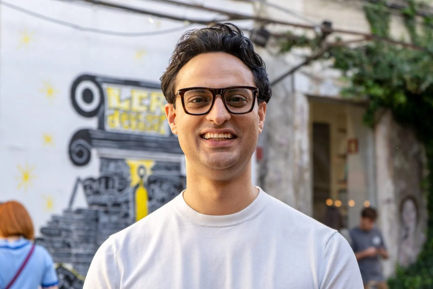 Koni Arora unterwegs in Lissabon, lachend vor einer bemalten Wand